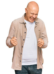 Wall Mural - Middle age bald man wearing casual clothes very happy and excited doing winner gesture with arms raised, smiling and screaming for success. celebration concept.