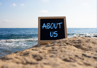 Canvas Print - About us symbol. Concept word About us on black chalk background. Beautiful sea background. Business and About us concept. Copy space