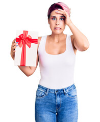 Poster - Young beautiful woman with pink hair holding gift stressed and frustrated with hand on head, surprised and angry face