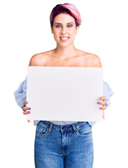 Poster - Young beautiful woman with pink hair holding cardboard banner with blank space looking positive and happy standing and smiling with a confident smile showing teeth