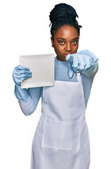 Poster - Young african american woman wearing apron washing dishes pointing with finger to the camera and to you, confident gesture looking serious