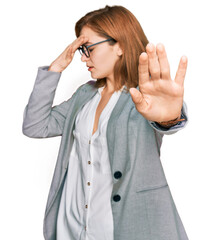 Poster - Young caucasian woman wearing business style and glasses covering eyes with hands and doing stop gesture with sad and fear expression. embarrassed and negative concept.