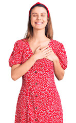 Wall Mural - Young beautiful girl wearing dress and diadem smiling with hands on chest with closed eyes and grateful gesture on face. health concept.