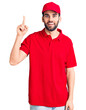 © Krakenimages.com - Young handsome man with beard wearing delivery uniform pointing finger up with successful idea. exited and happy. number one.