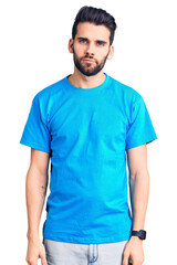 Wall Mural - Young handsome man with beard wearing casual t-shirt relaxed with serious expression on face. simple and natural looking at the camera.