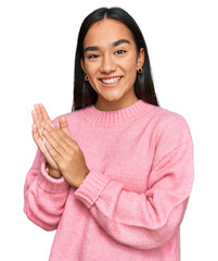 Wall Mural - Young asian woman wearing casual winter sweater clapping and applauding happy and joyful, smiling proud hands together
