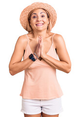 Canvas Print - Young blonde woman wearing summer hat praying with hands together asking for forgiveness smiling confident.