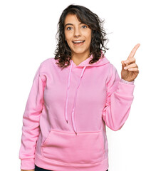 Wall Mural - Young hispanic woman wearing casual sweatshirt with a big smile on face, pointing with hand finger to the side looking at the camera.