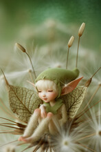 A Tiny Elf In Green Cap And Clothes Sitting  On A Leaf 