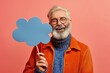 An older man smiling and holding a sign shaped like a cloud.