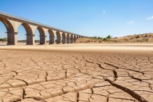 An Arched Bridge Spans Over A Cracked, Dry Riverbed, Symbolizing Infrastructure Resilience Amidst Drought Conditions. Bridge Over Cracked Earth In Drought