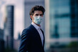 A portrait of a young businessman in a financial district with a protective face mask
