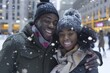 Happy African American couple embracing in snowy New York City with tall buildings in background, wearing warm coats and hats