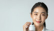 portrait of an Asian model in a minimalist studio setting her skin glowing with health and vitality. The models face is the picture of natural beauty