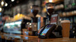 Close-up view of a mobile payment transaction at a coffee shop showing detailed textures of the smartphone and payment device