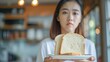 Asian young woman don't like to eat a slice of white bread on a platter in her hand