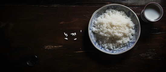 Poster - A recipe for a simple dish a bowl of rice is placed on a wooden table, next to a glass of milk. The ingredients sit in a circle of light from the automotive lighting, casting shadows in the darkness