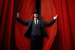 Cinematic posed portrait of magician actor over red velvet stage curtain