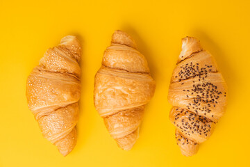 Wall Mural - Flat lay of freshly baked croissants on the yellow background. Traditional French pastry with a copy space for a free text
