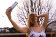 © Marino Bocelli - young charming blonde sporty woman in sportswear posing taking a selfie outdoors