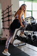 © Marino Bocelli - young charming blonde woman in sportswear lifting dumbbells in a gym