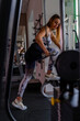 © Marino Bocelli - young charming blonde woman in sportswear lifting dumbbells in a gym