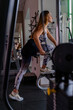 © Marino Bocelli - young charming blonde woman in sportswear lifting dumbbells in a gym