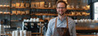 Portrait of a handsome barista in an apron on a bar background