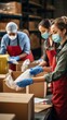 © liliyabatyrova - Volunteers in masks, uniforms and gloves sorting and packing food in cardboard boxes indoors. The concept of Charity, Donation, Distribution of free Food to the homeless and the poor.
