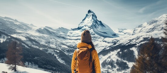 Poster - A traveler with a backpack admires the snowy mountain against a backdrop of a clear blue sky, creating a stunning natural landscape art piece with the wind blowing through the snowy peaks