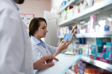 Wall Mural - Professional pharmacists near shelves with merchandise in modern drugstore