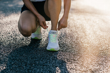 Poster - Woman runner tying shoelace on sunny tropical park trail