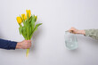 A man puts a bouquet of yellow tulips in a jar of water.