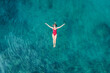 Aerial View of a Woman in Red Swimsuit Floating Serenely on the Crystal Clear Ocean Waters During Midday