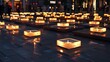 Candlelight vigil with numerous candles in square holders on pavement at dusk, symbolizing remembrance or event.