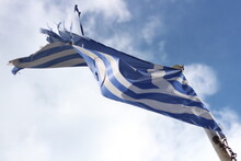 Resilience And Pride: Tattered Greek Flag Against Blue Sky