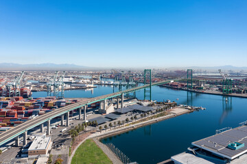 Aerial view of the Vincent Thomas Bridge. Port with cranes and several colorful containers. Sunny day. San Pedro, CA, USA