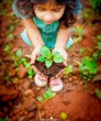 Aerial perspective: A young girl lovingly tends to a small plant, symbolizing commitment to nature and life on Earth Day. The image captures the essence of environmental care and growth potential, pro