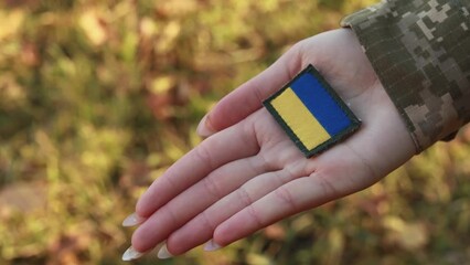 Wall Mural - Close up velcro patch, flag of Ukraine on military uniform soldiers hand. Female servicewoman dressed in camouflage, symbol of independence. Armed Forces of Ukraine. Woman serving in ukrainian army
