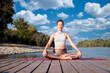Full length of a woman sitting in lotus pose and practicing yoga outdoor by the Danube river