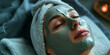 Cosmetic procedures. Close-up portrait of a beautiful girl lying and applying a face mask in a green clay spa. Daispa.