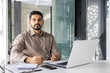 © Liubomir - Focused Indian businessman engaged in work with a laptop at his modern office. He looks serious and determined, signaling professionalism.