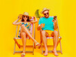 Young couple wear summer clothes sit in deckchair and use mobile phone. Tourist travel concept
