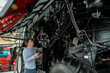 © scharfsinn86 - Serviceman with digital tablet on a next to ombine harvester with open hood..