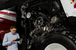 © scharfsinn86 - Serviceman with digital tablet on a next to ombine harvester with open hood..