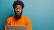 Shocked African man while watching in on laptop isolated blue background .Image of excited screaming young man sitting isolated over blue background. Looking camera.Portrait African American man