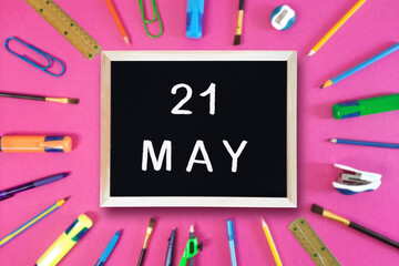 May 21 written in chalk on black board. Calendar date 21th of May on chalkboard on pink blurred school stationery background. Event schedule date. School, study, education concept. Month of spring.