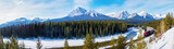 Fototapeta Sport - Panorama of Morant's Curve in Banff National Park as red cargo train passes through in Winter with Mount Temple and Paradise Valley in the background.