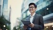 © Exnoi - A man wearing a suit and glasses is holding a tablet in his hand