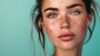 Close-up portrait of a young woman with freckles and blue eyes against a teal background. Intense gaze and natural beauty concept for design and print